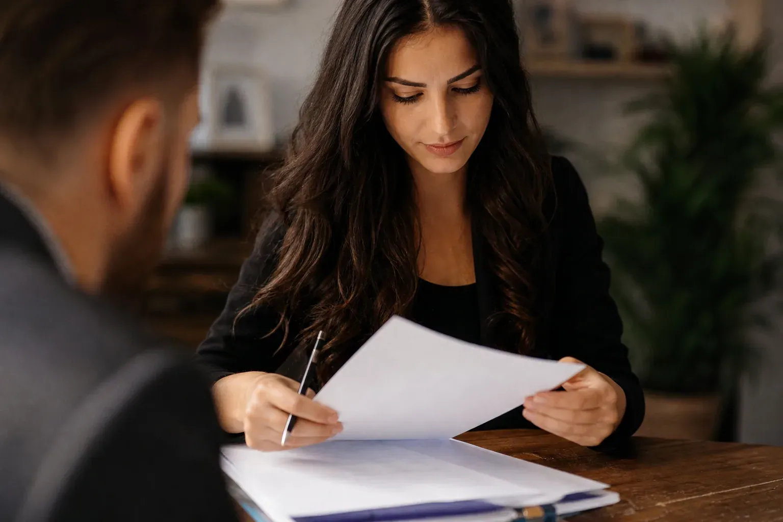 Personne relisant la clause bénéficiaire de son contrat d'assurance-vie à une table, documents et stylo, lumière naturelle.