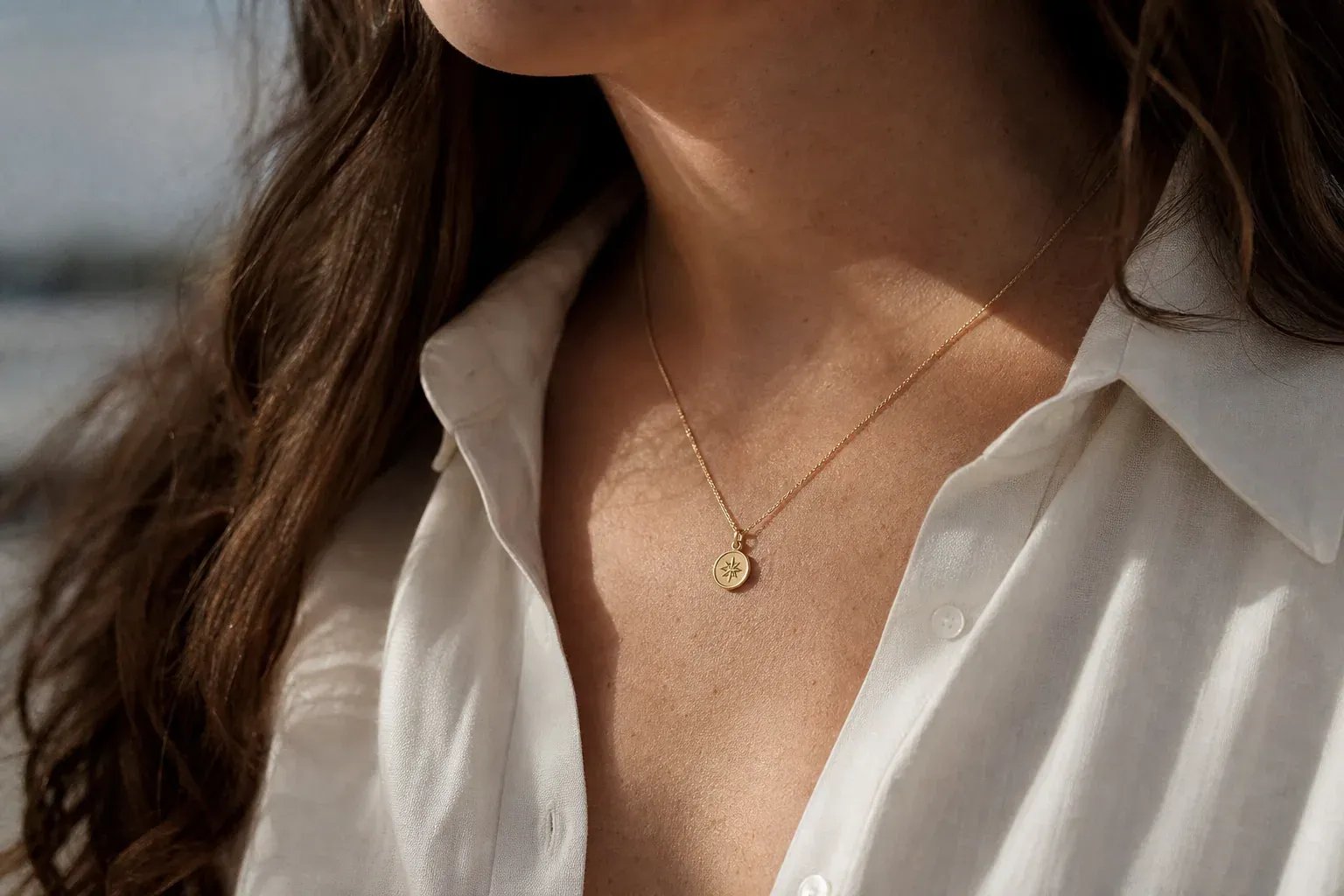 Gros plan réaliste d’une chaîne en or portée au cou avec un pendentif symbolique, sur fond neutre et en lumière naturelle.