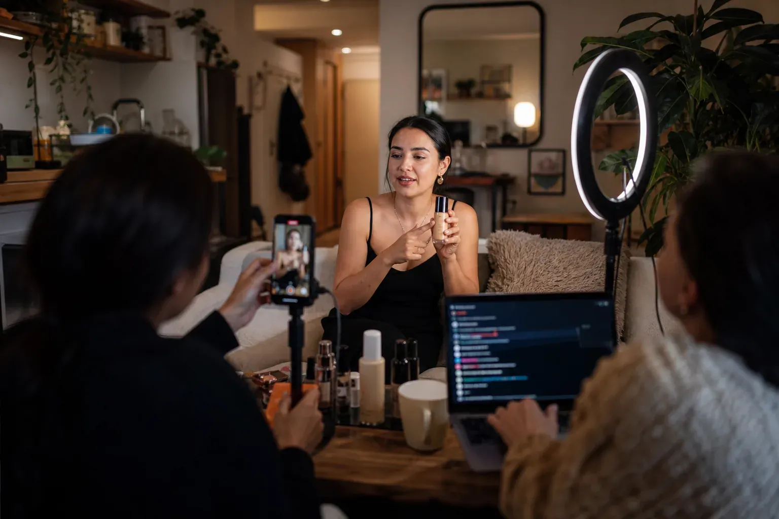 Créatrice en direct sur TikTok Live, filmée dans un petit studio domestique, avec un smartphone sur trépied, une lumière de studio et des produits à présenter.