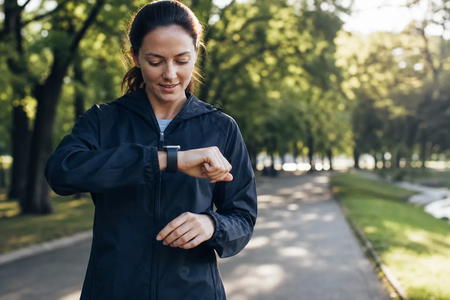Une personne consulte sa montre connectée pendant une marche en extérieur, dans une scène réaliste de suivi santé au quotidien.