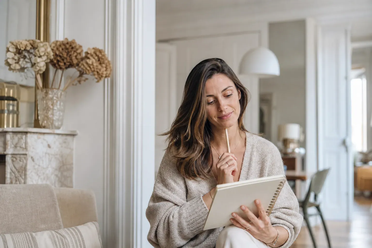 Une femme consulte un carnet de prénoms dans un intérieur lumineux, avec une atmosphère douce et moderne.