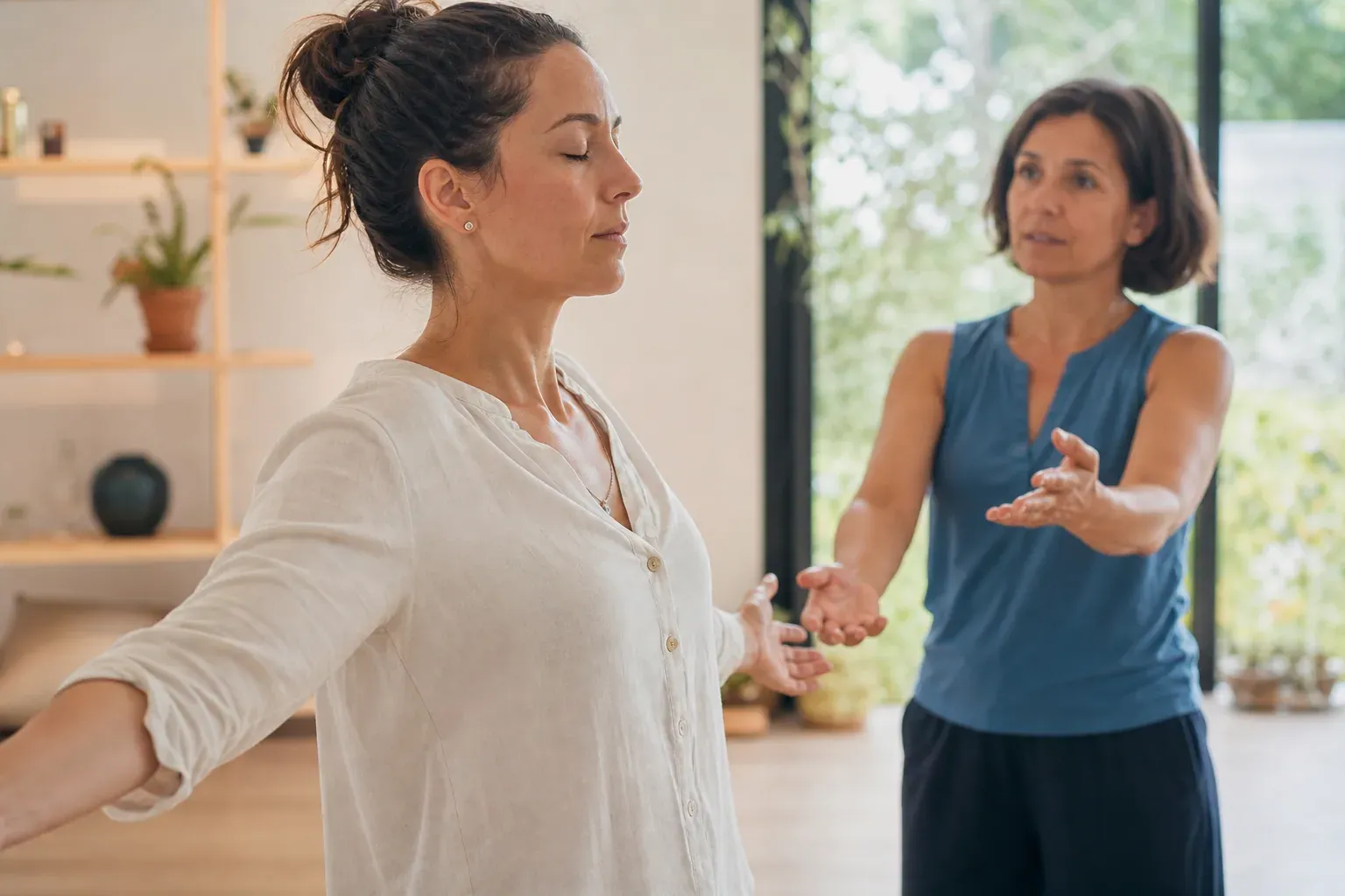 Une femme pratique des exercices de respiration et de mouvements doux avec un sophrologue dans une salle lumineuse et apaisante.