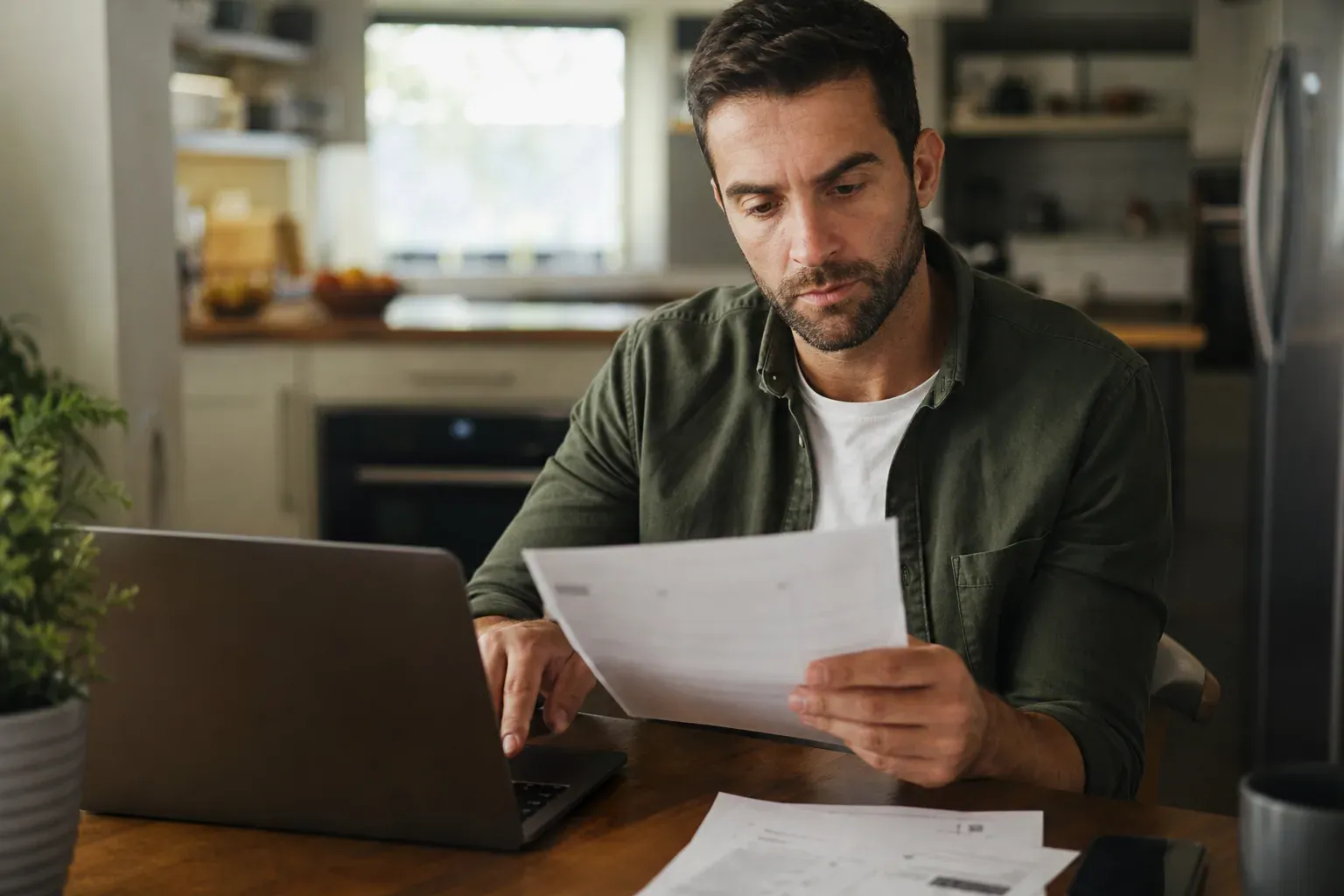 Personne consultant son avis de taxe foncière et réglant le paiement en ligne sur un ordinateur portable, lumière naturelle.